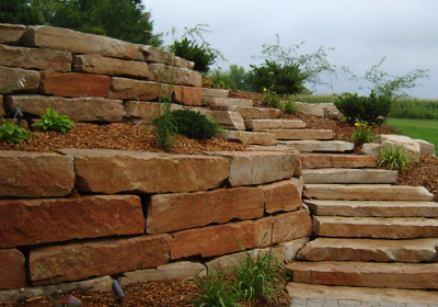 Layered stone retaining wall with matching stone steps built into a landscaped slope